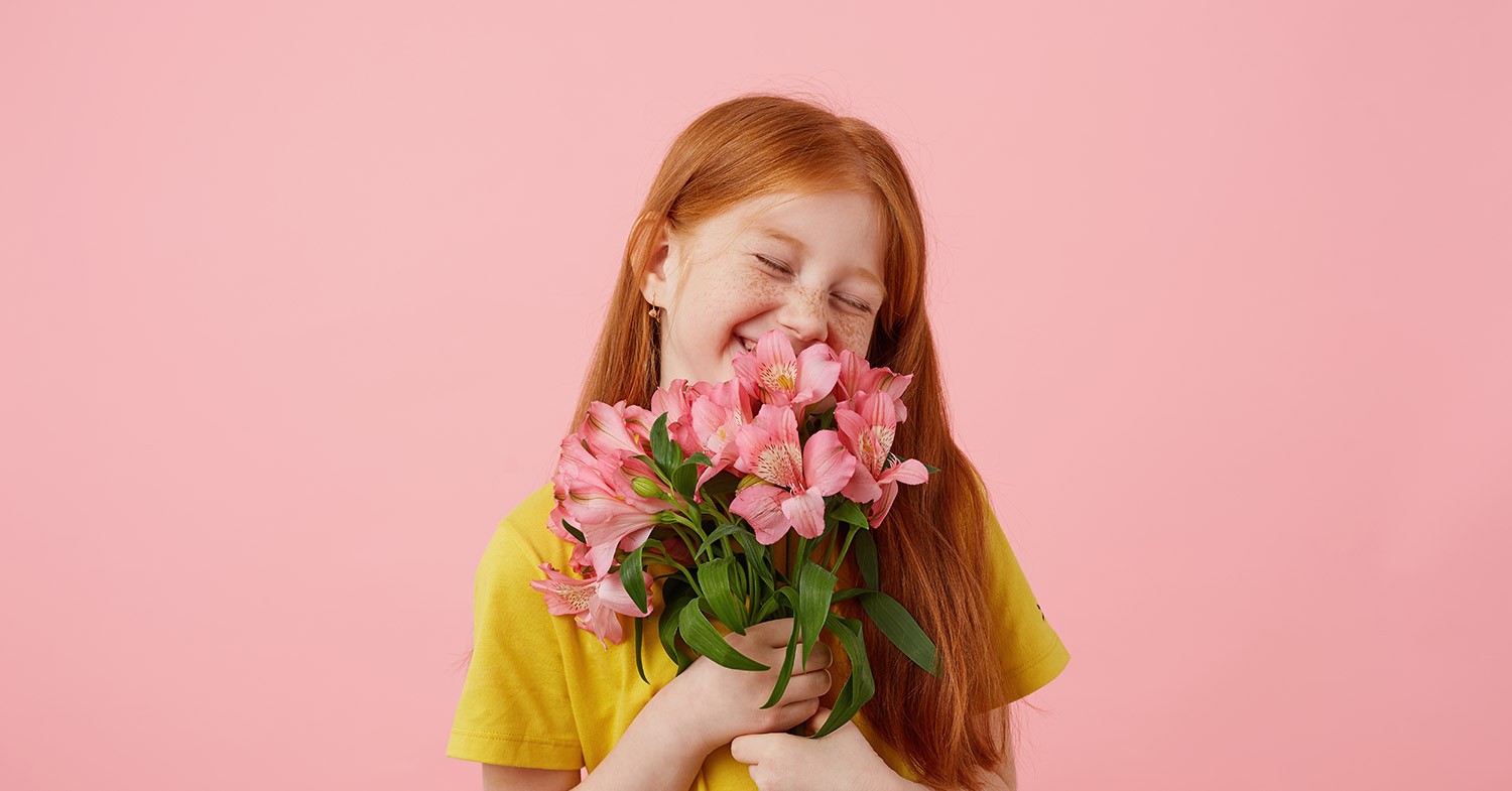 یک دختر شاد به همراه گل با پشت زمینه صورتی
